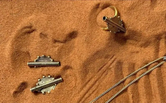 Ensemble de bijoux SYKA photographiés sur le sable.